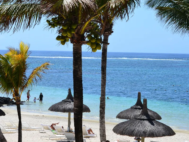 Playa con palmeras y sombrillas de paja en Mauricio