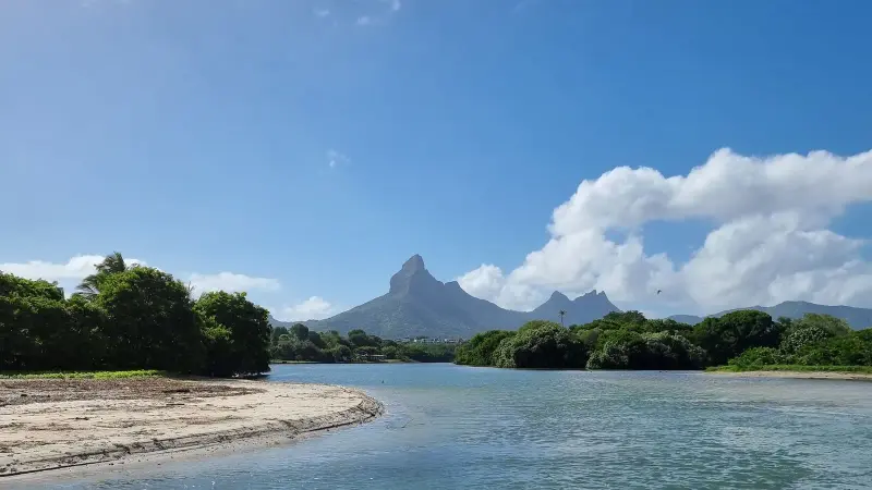 Laguna y orilla de arena con una montaña puntiaguda detrás