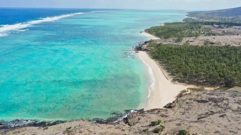 Vista aérea de una playa que se curva junto a una laguna turquesa