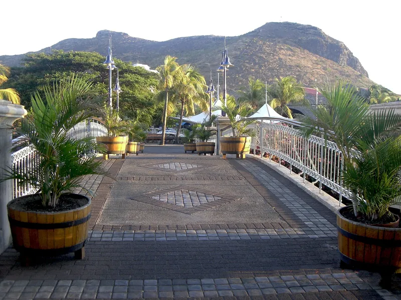 Pasarela con palmeras en el Caudan Waterfront, con montañas detrás
