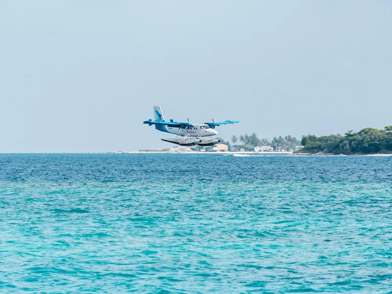 Hydravion volant au ras d'une eau turquoise